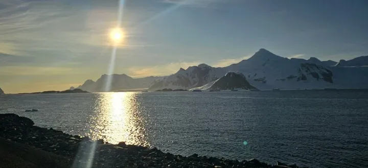 a picture of the sun rising above the icy waters of the Antarctic